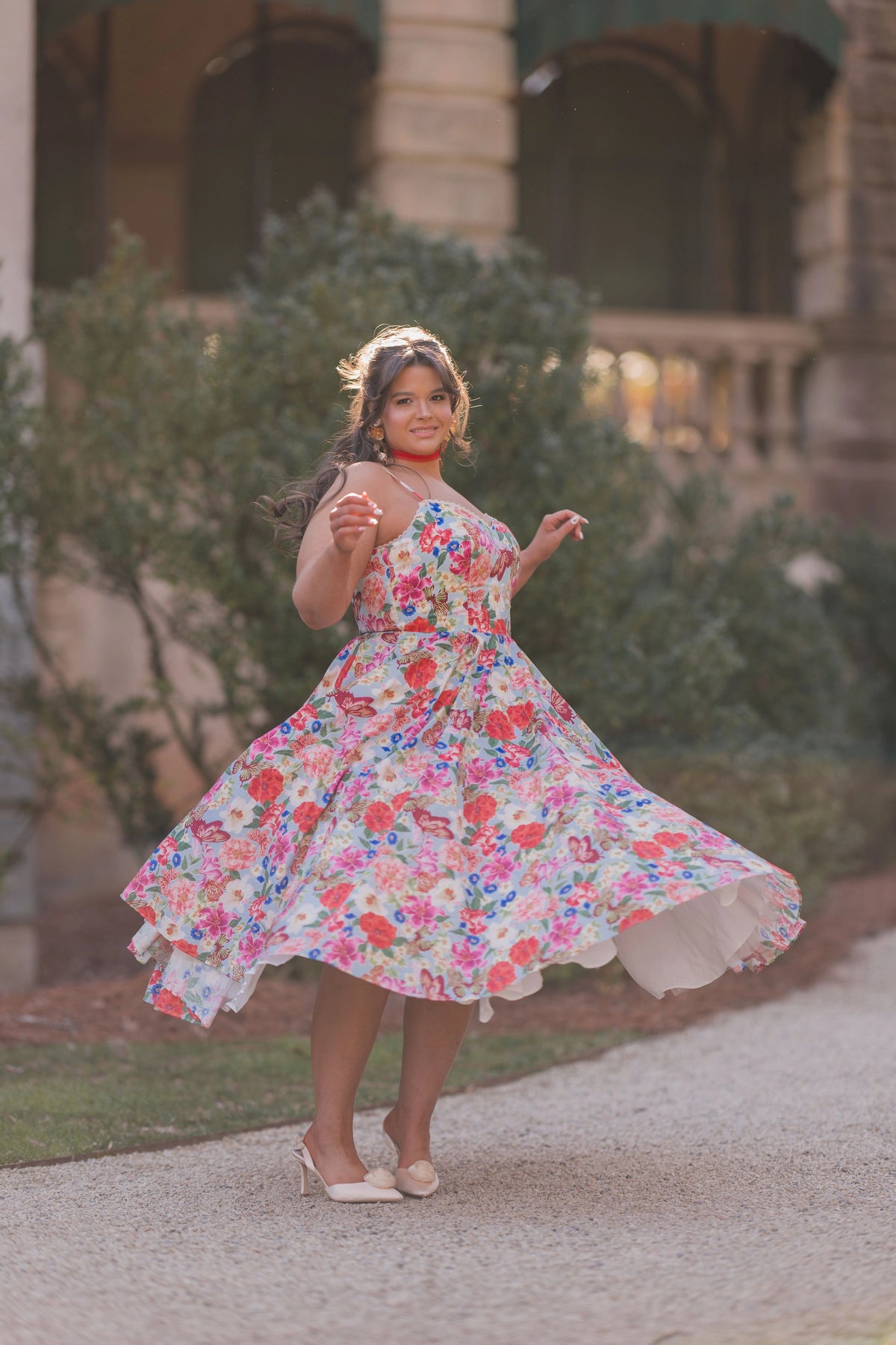 The image shows a woman in a colorful dress walking down a street, with a building and trees in the background. She is wearing footwear, suggesting she is ready to take on the world.